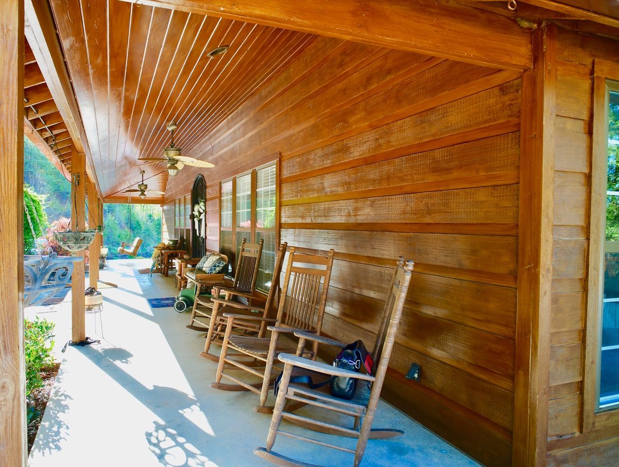 There are many rocking chairs on the porch of a log cabin.