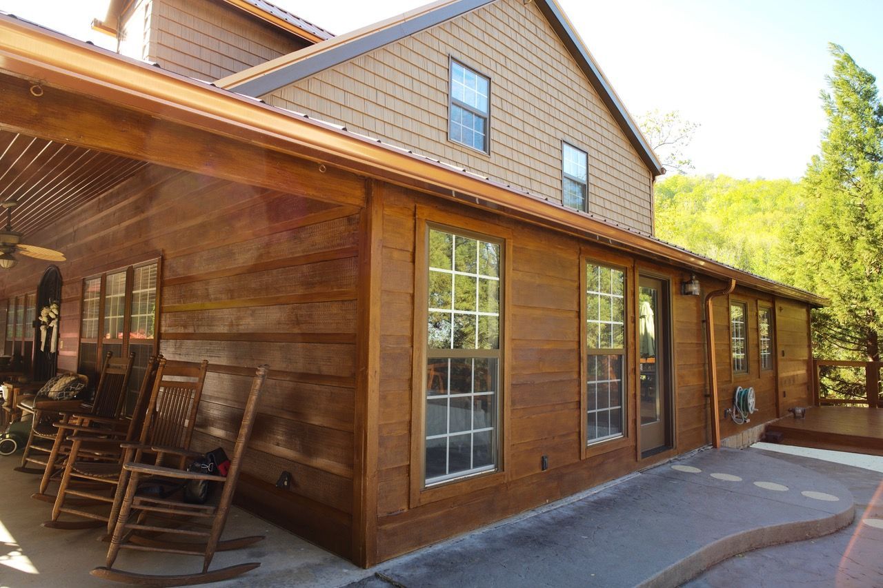 A large wooden house with rocking chairs on the porch.