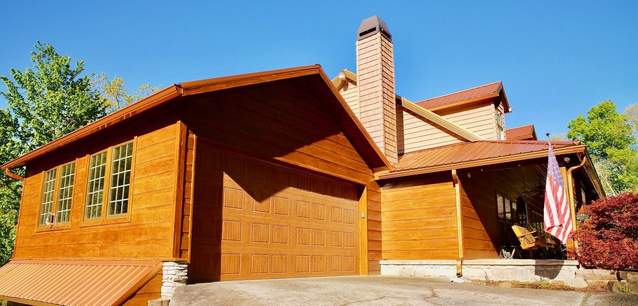 A large wooden house with a red tile roof and an american flag on the porch.