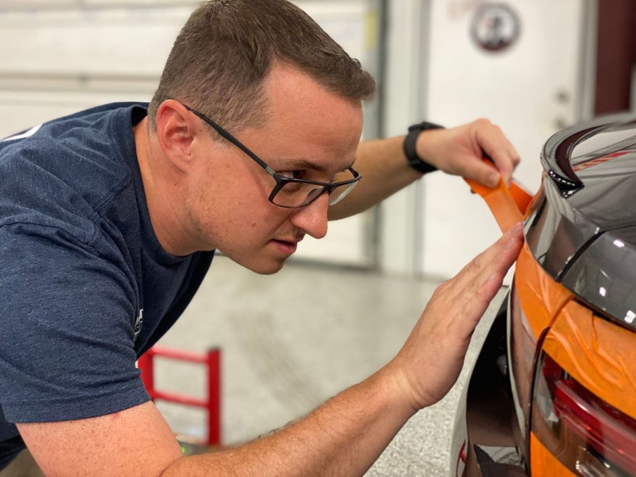 A man is cleaning a green car with a towel.