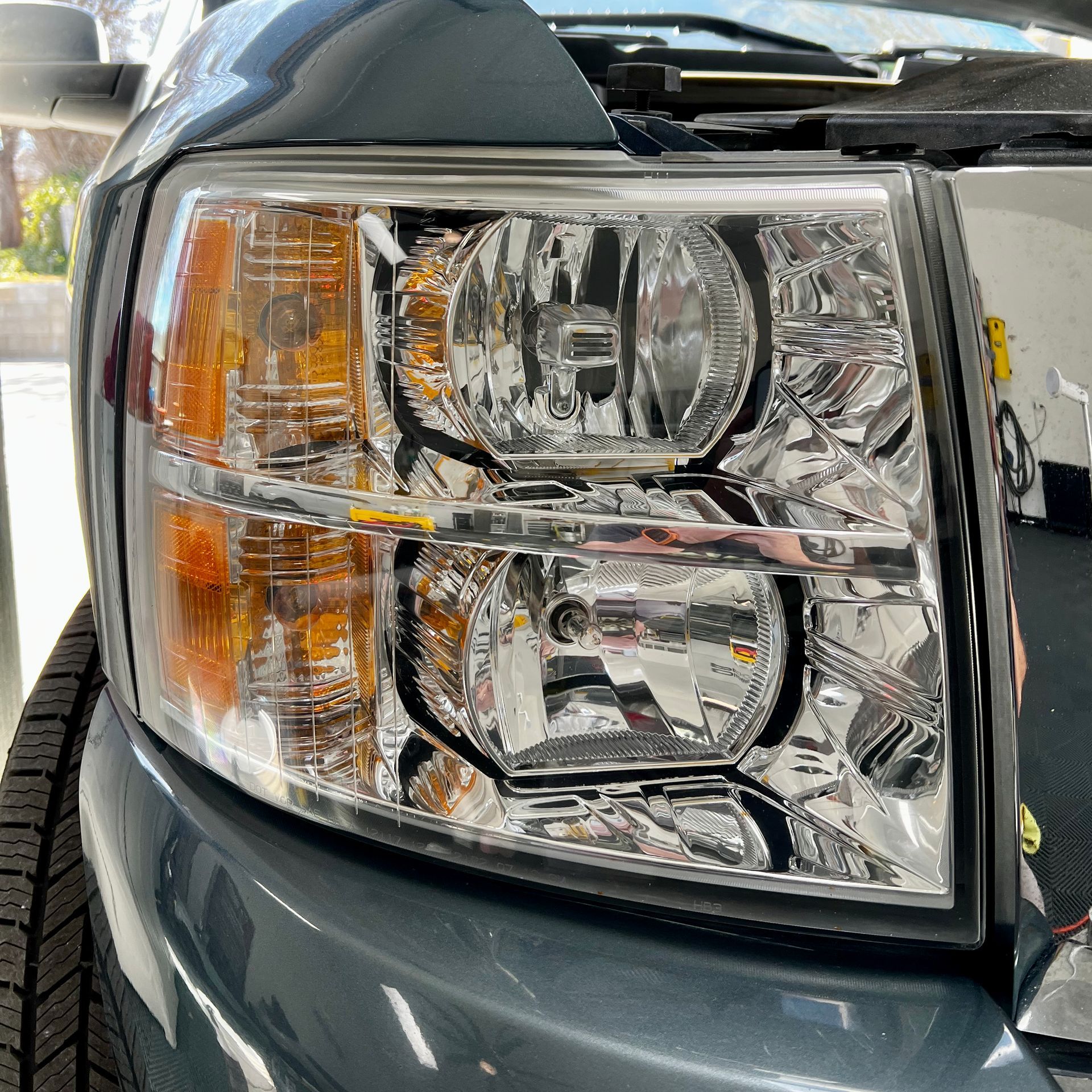 A close up of a car 's headlight with the hood open.