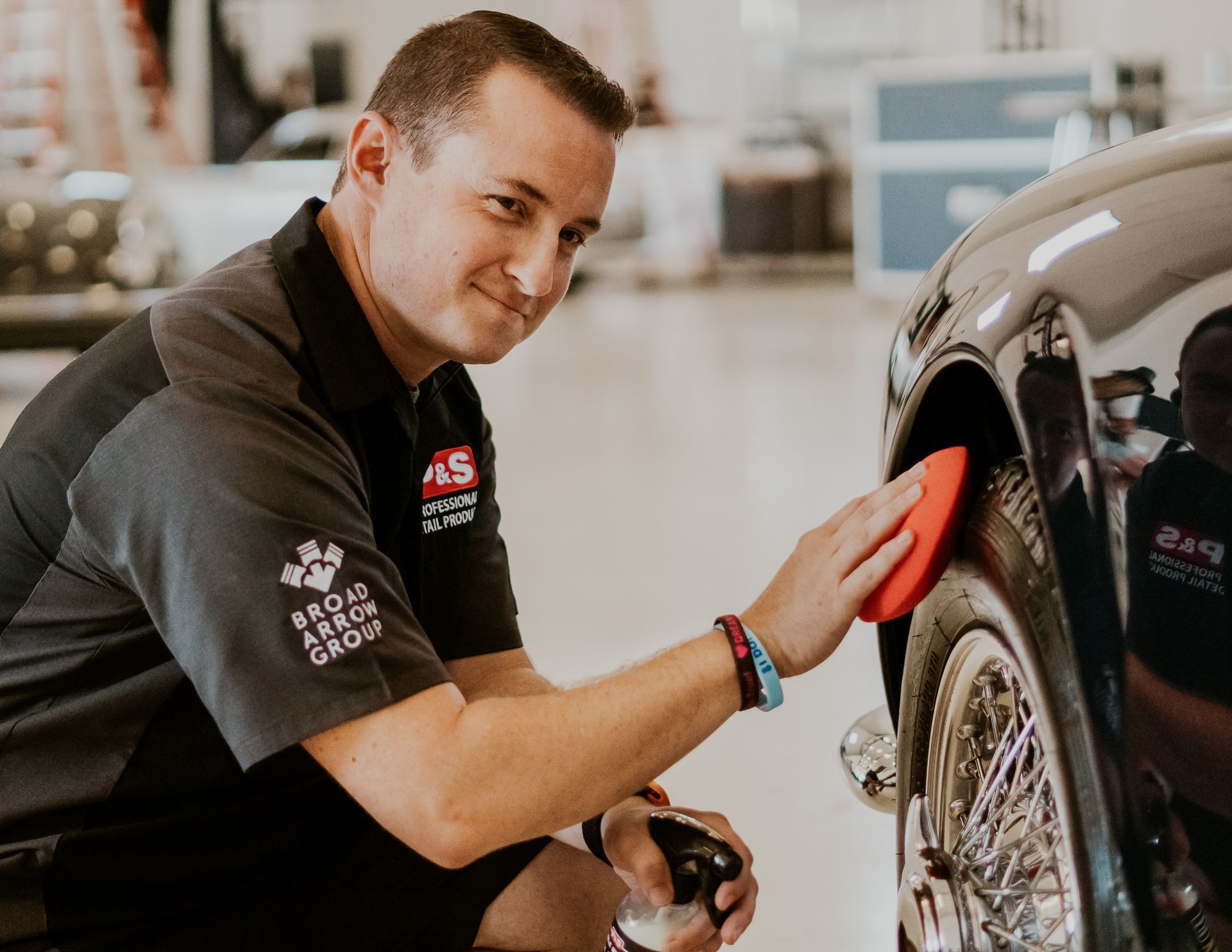 A man is polishing the side of a car with a sponge.