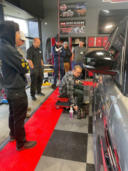 A group of men are working on a car in a garage.