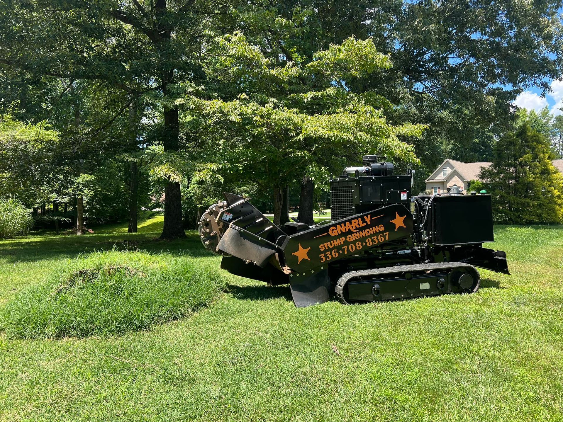 A tree stump grinder is sitting in the middle of a lush green field.