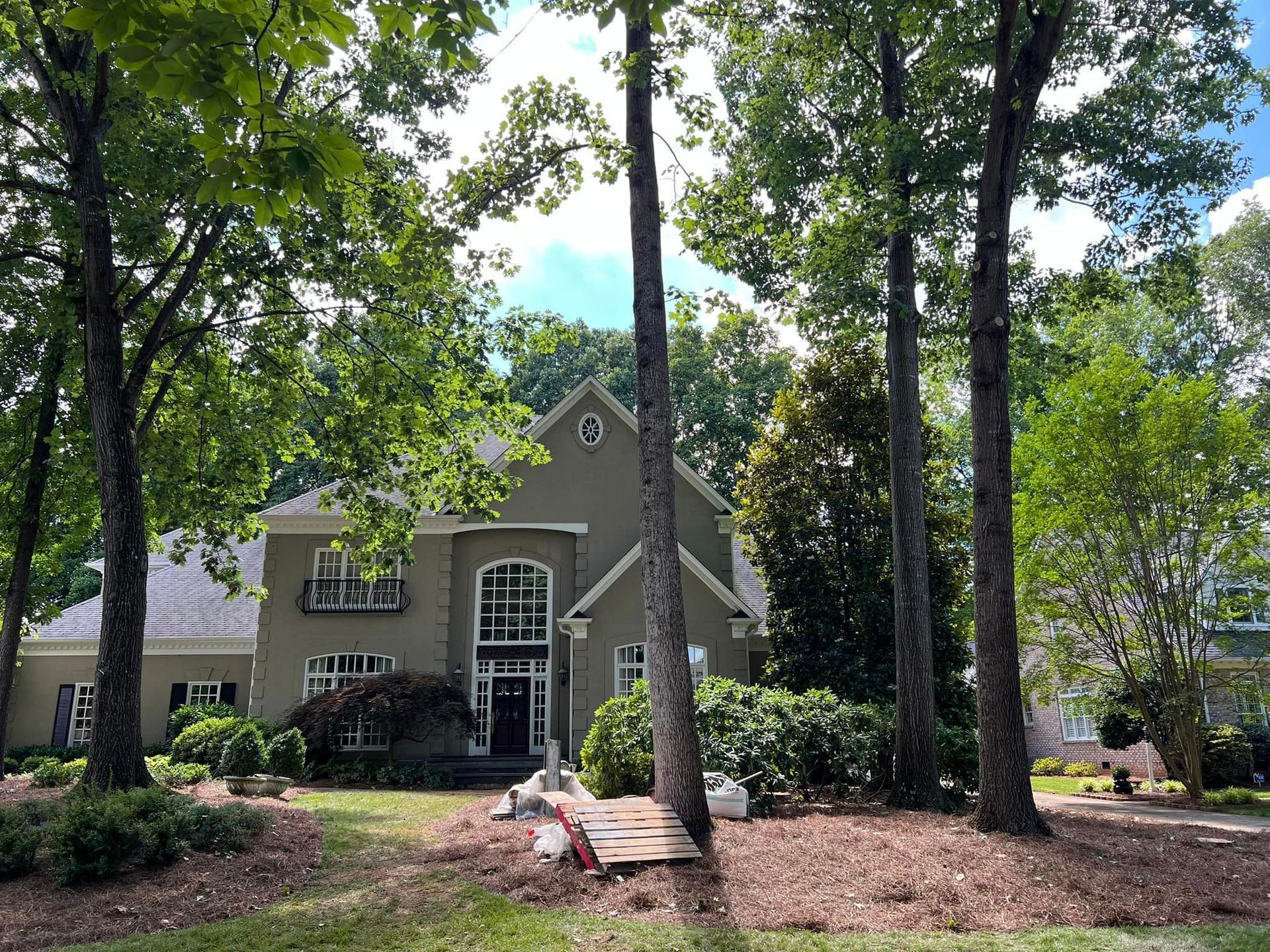 A large house is surrounded by trees on a sunny day.