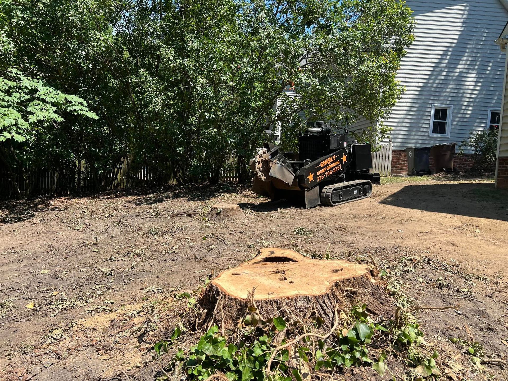 A stump grinder is sitting next to a tree stump in a yard.