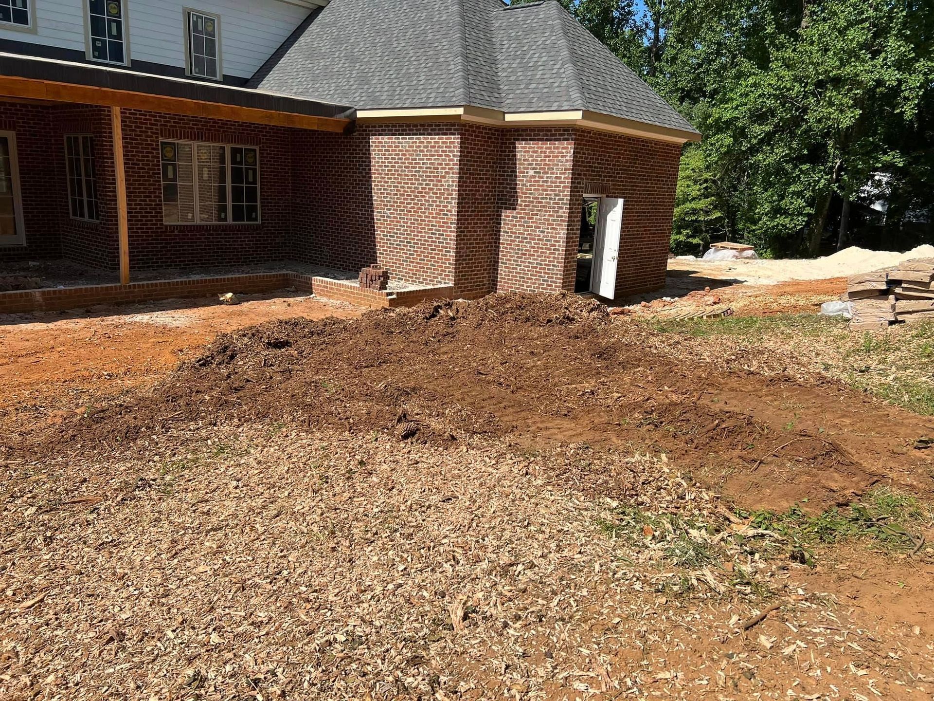 A large pile of dirt is in front of a house under construction.