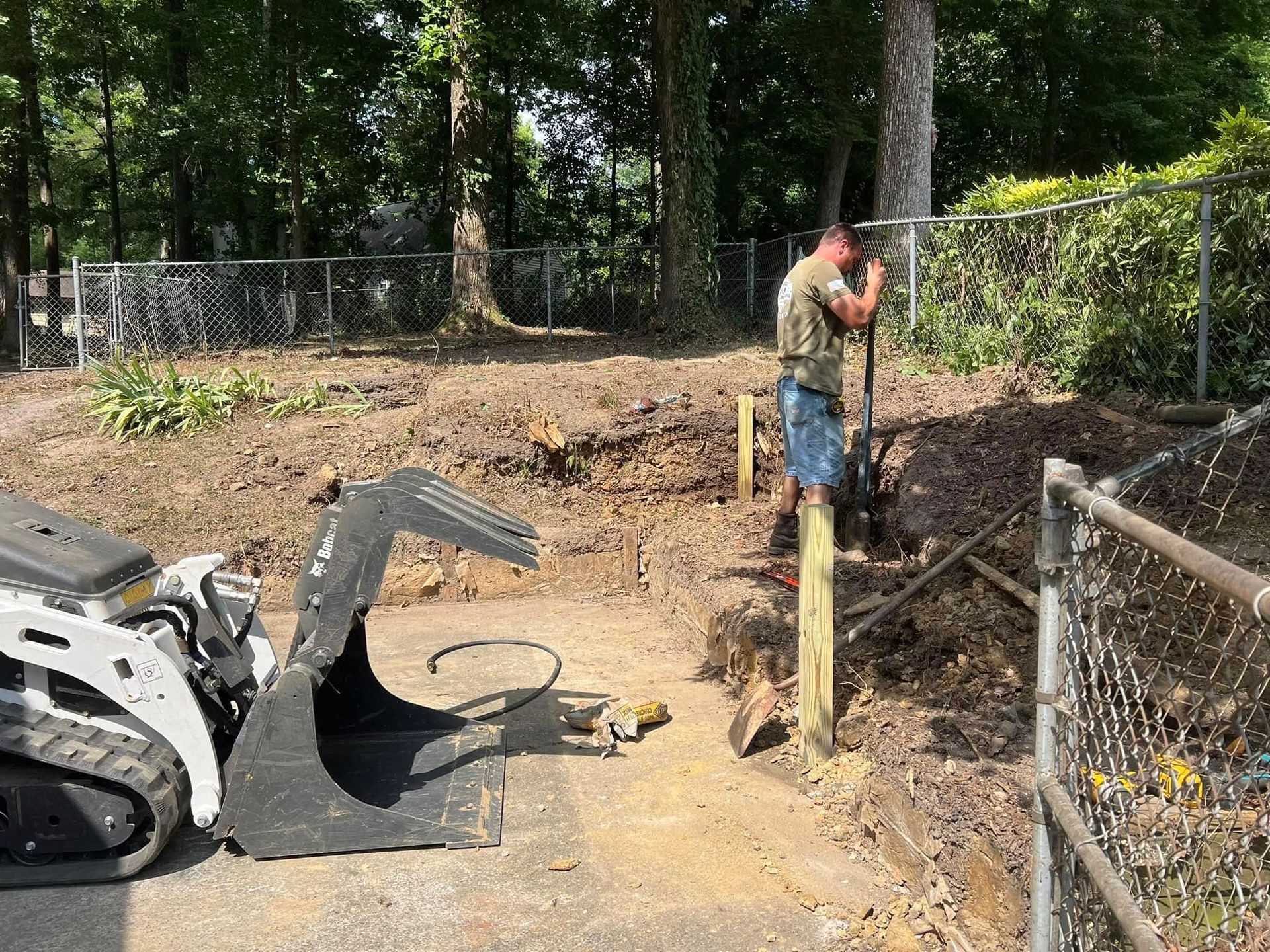 A man is digging in the dirt next to a bulldozer.