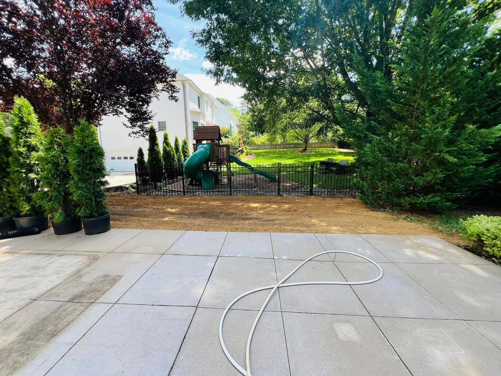 A basketball court in a backyard with a playground in the background