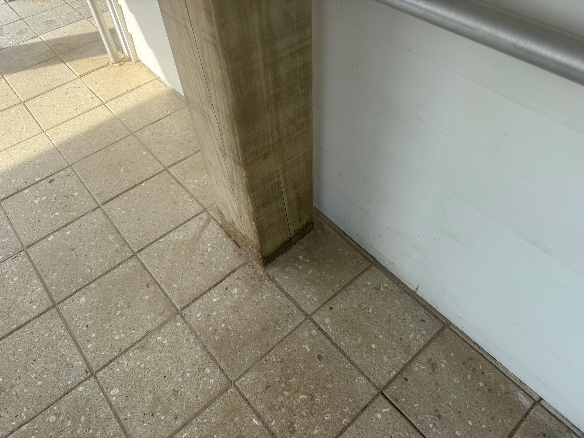 Concrete tiled floor, column, and white wall with handrail.