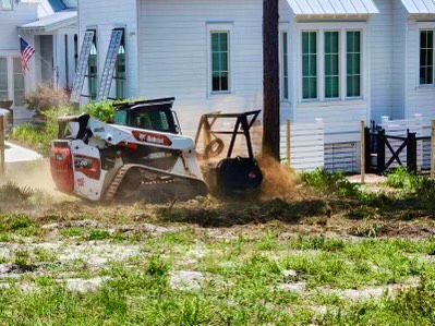 A bulldozer is moving dirt in front of a white house.