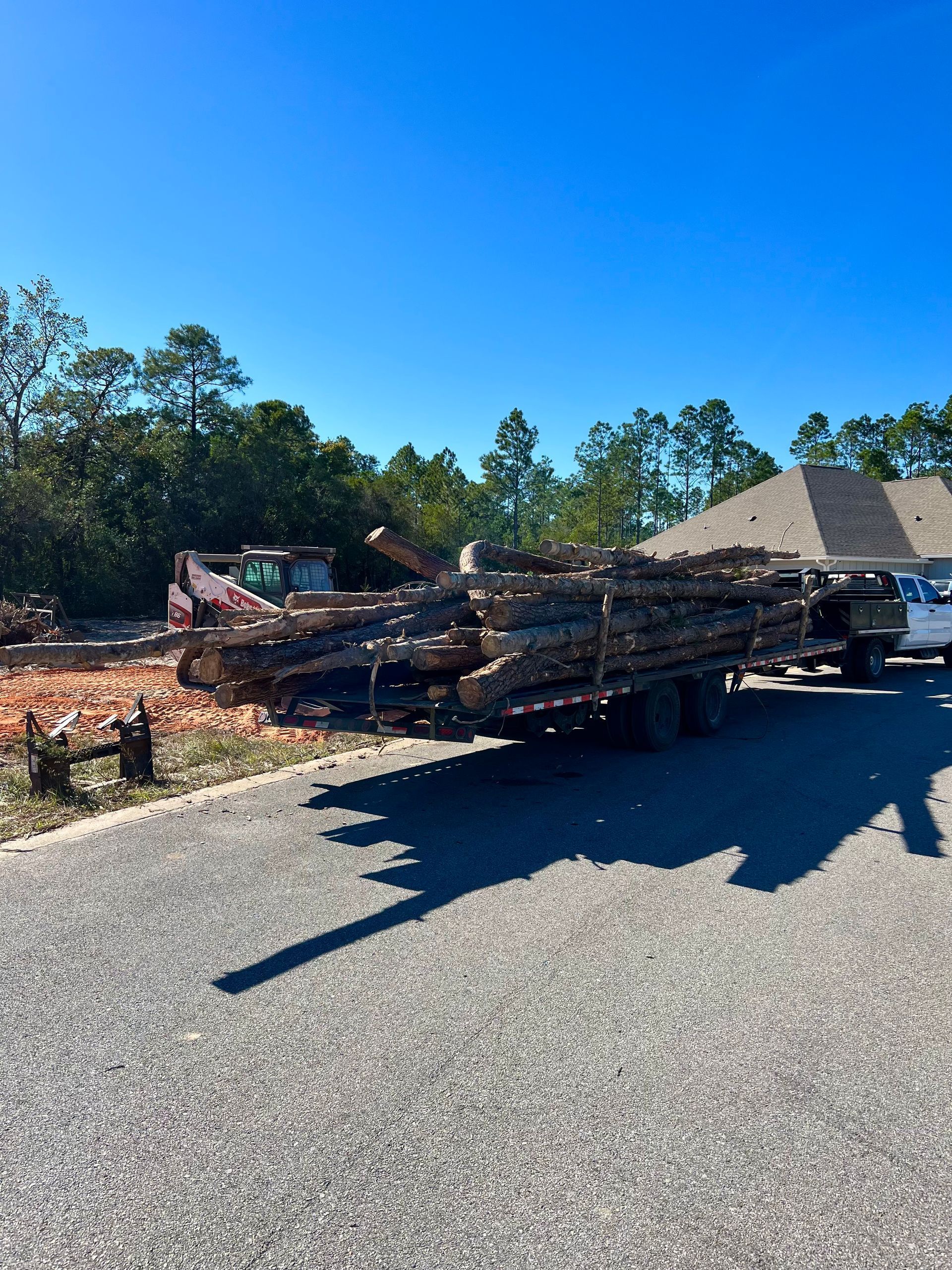 A truck is carrying a large stack of logs on a trailer.