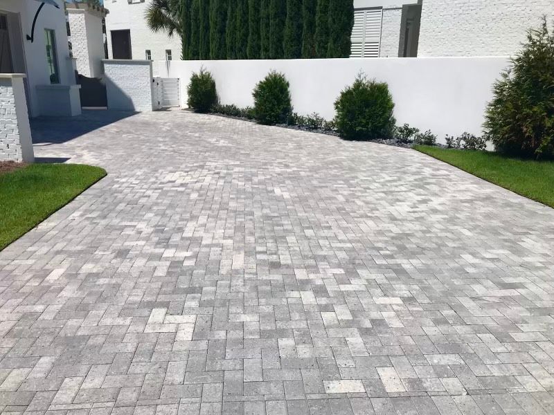 A brick driveway leading to a white house