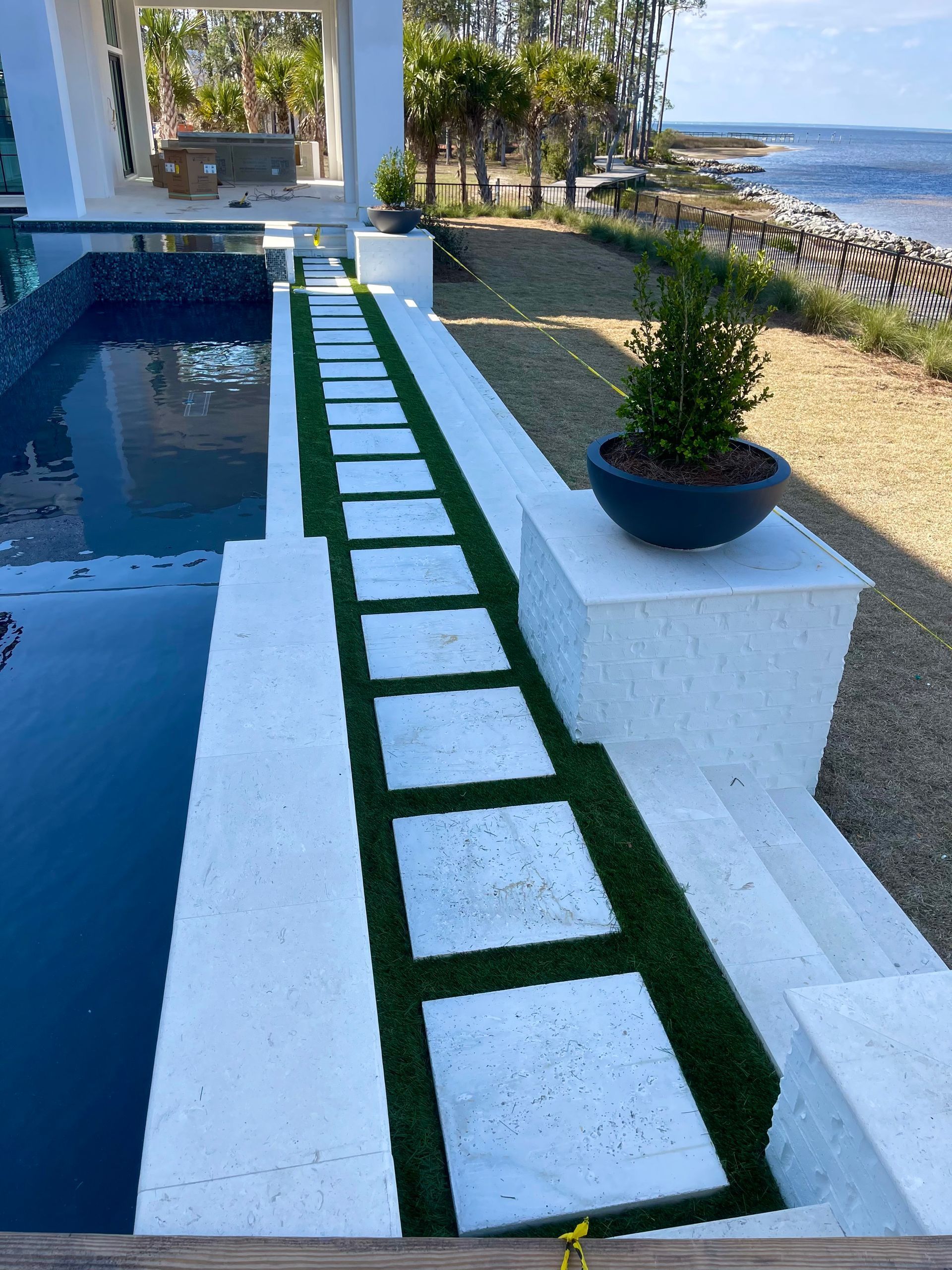 A walkway leading to a swimming pool with a potted plant in the middle.