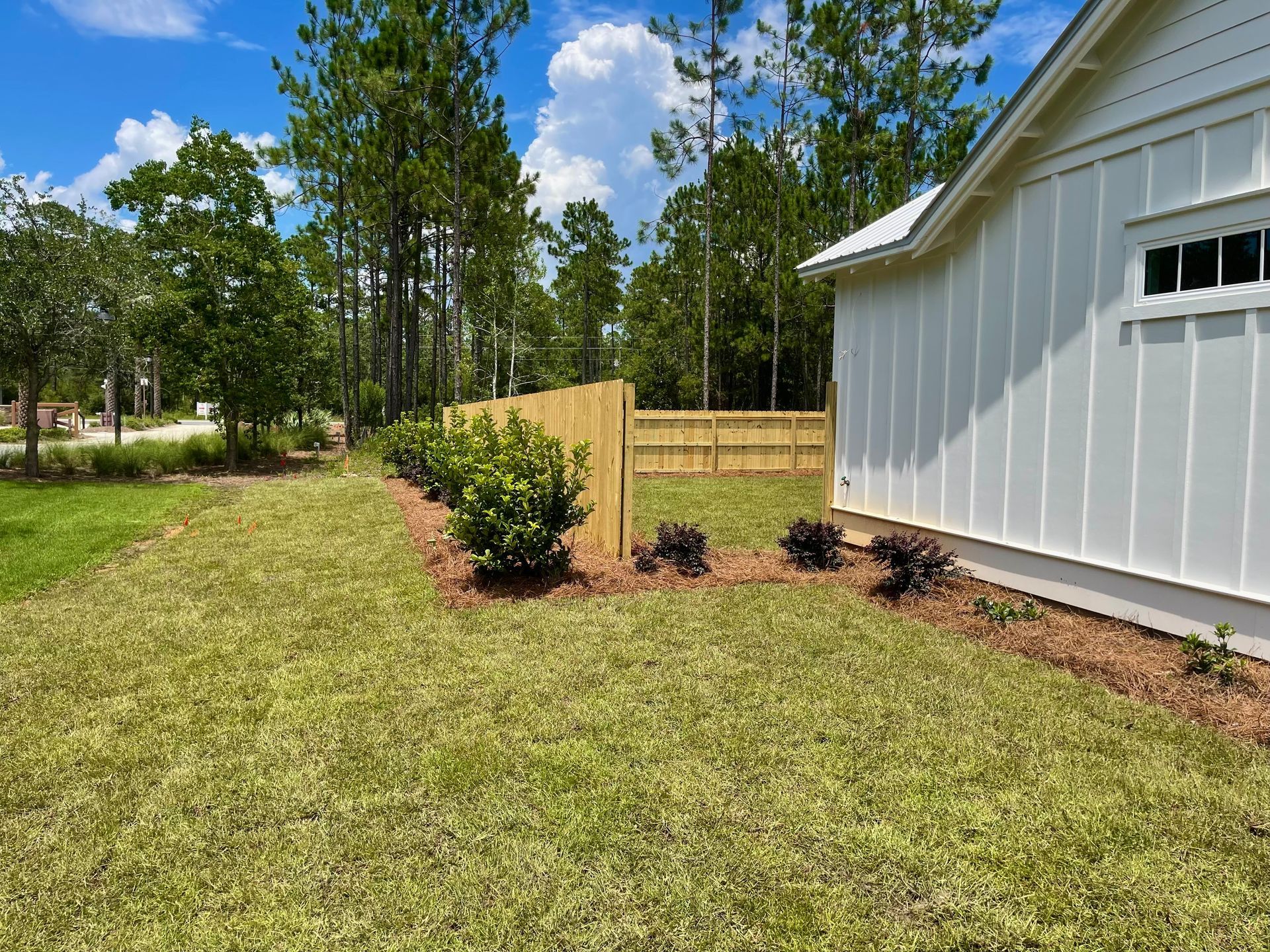 A white house with a wooden fence in the backyard.