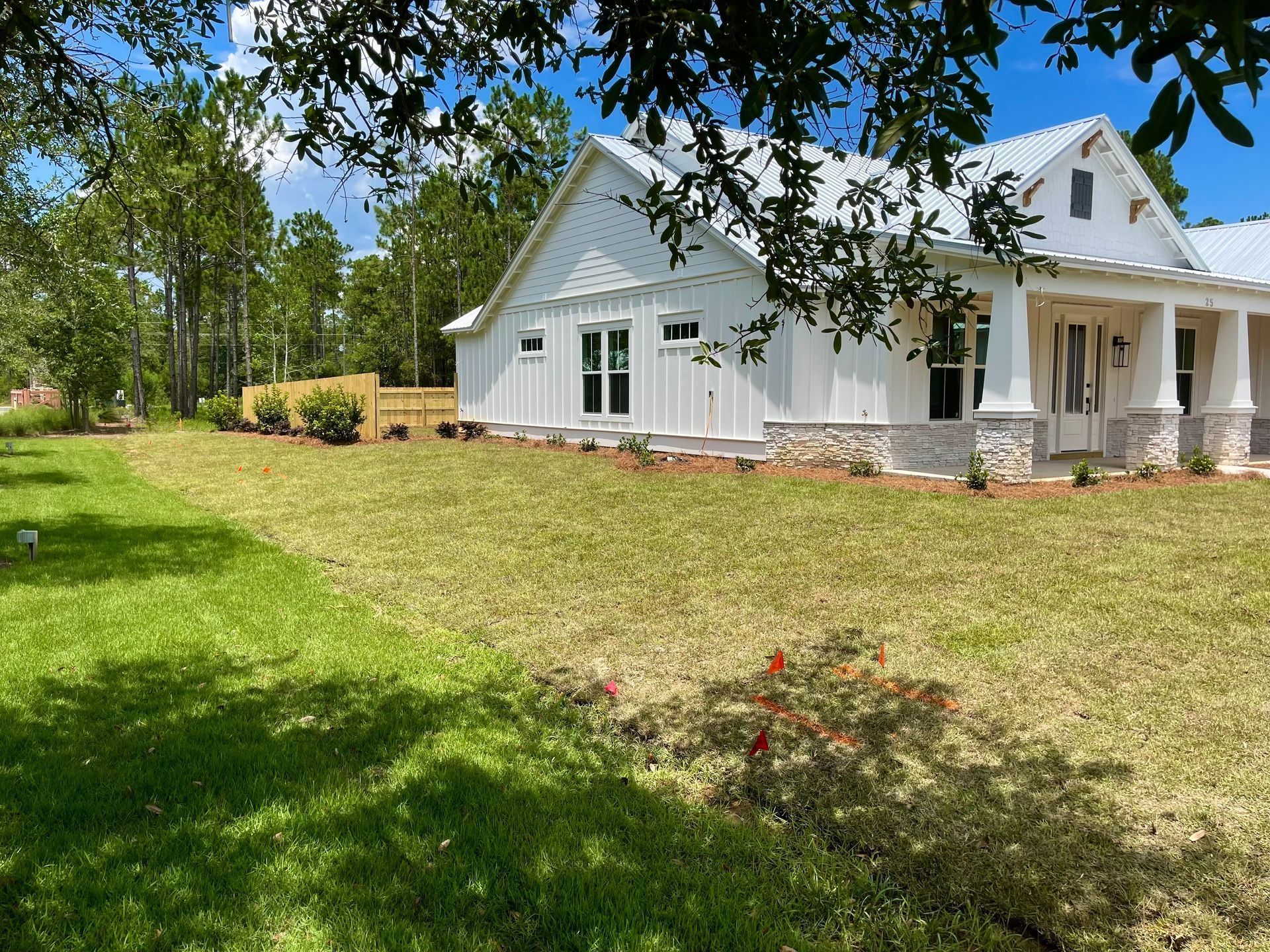 A large white house is sitting on top of a lush green field.