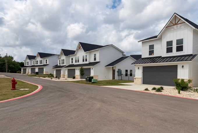 A woman is pouring a drink into a glass at a dinner table.