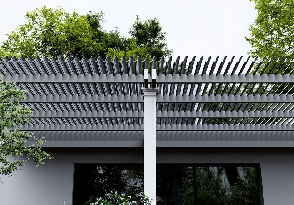 Gray pergola roof with adjustable louvers, white post, and green trees in background.