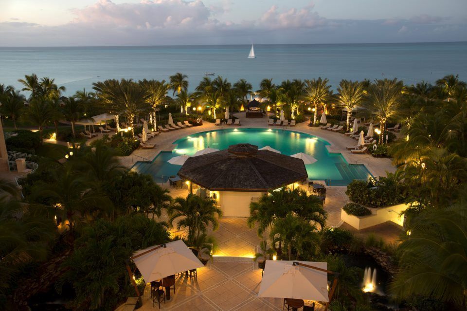 An aerial view of a resort with a large swimming pool surrounded by bright lights.