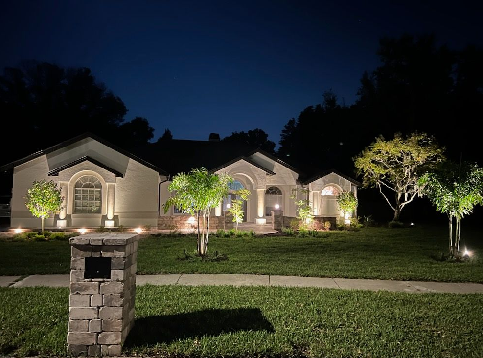 An front view of a home featuring a full landscape lighting design.
