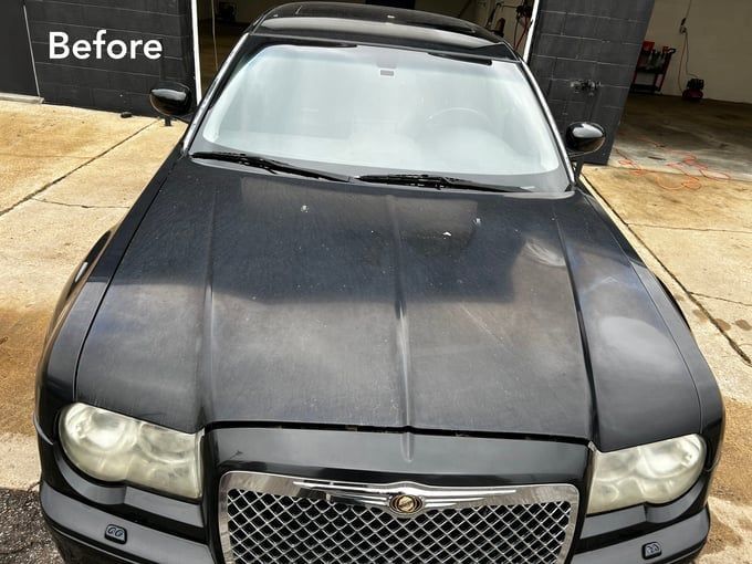 Black Chrysler 300 car before detailing, showing dull paint and dirty headlights. 