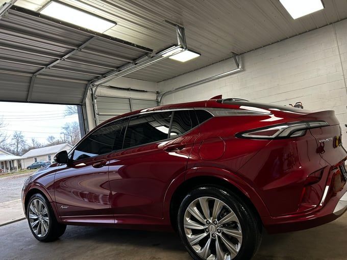 Red Buick Envista SUV in a garage with the door open.