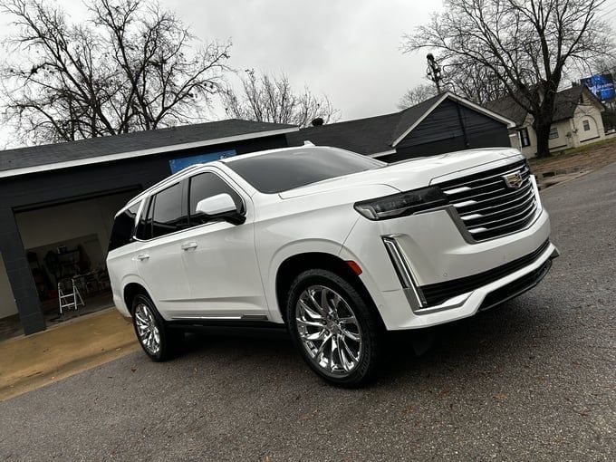 White Cadillac Escalade parked on a street in front of a building.