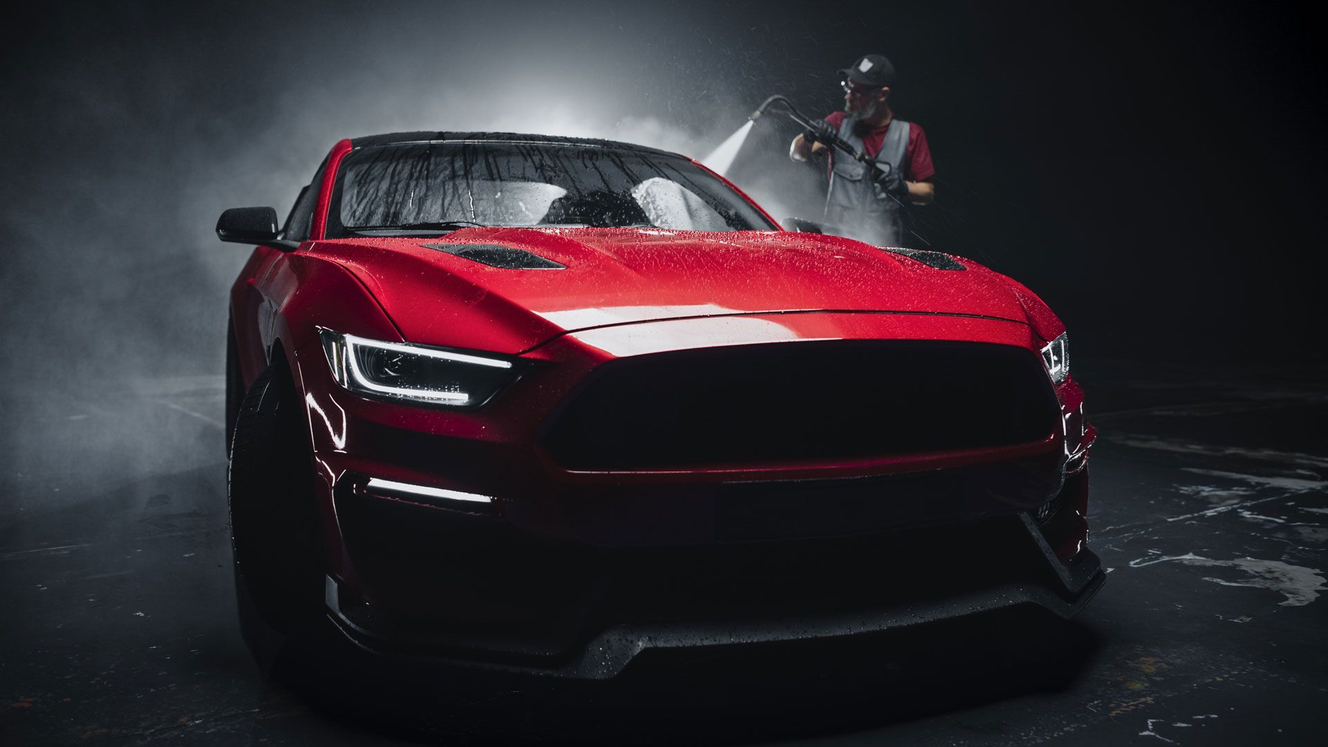 Red Ford Mustang being washed by a person with a pressure washer; water droplets and fog.