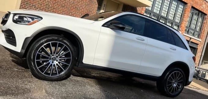 White Mercedes SUV parked outside on a brick road.