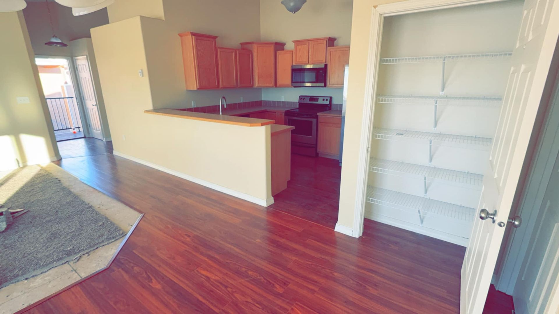A living room with hardwood floors and a kitchen in the background.