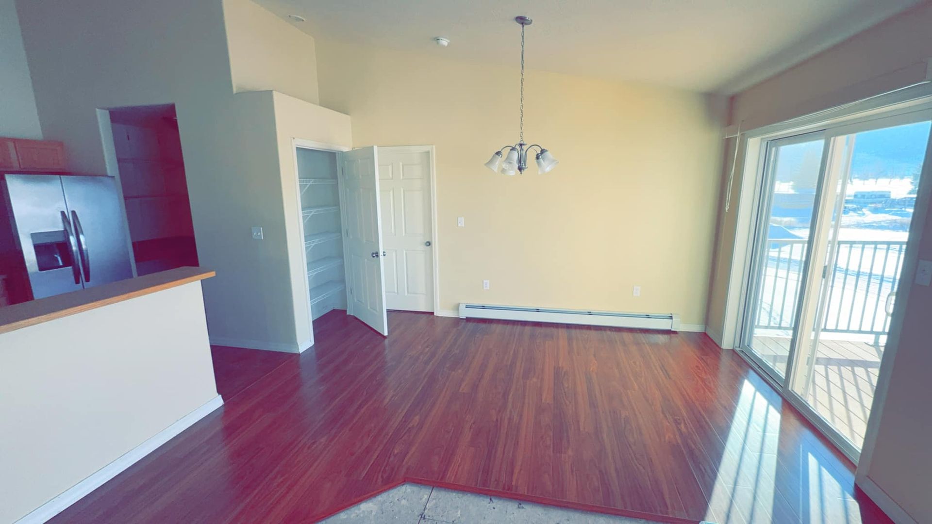 An empty living room with hardwood floors and sliding glass doors.