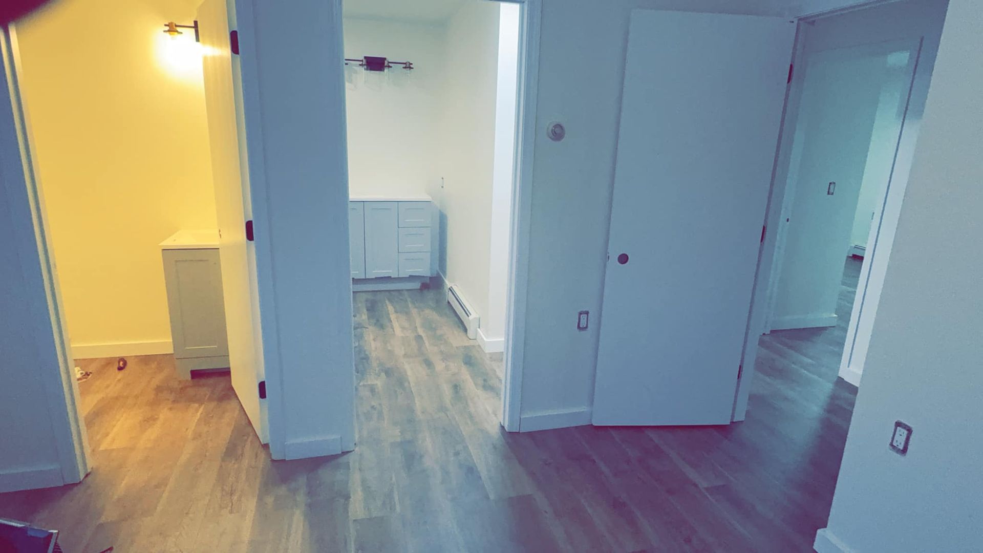 A hallway in a house with hardwood floors and white walls.