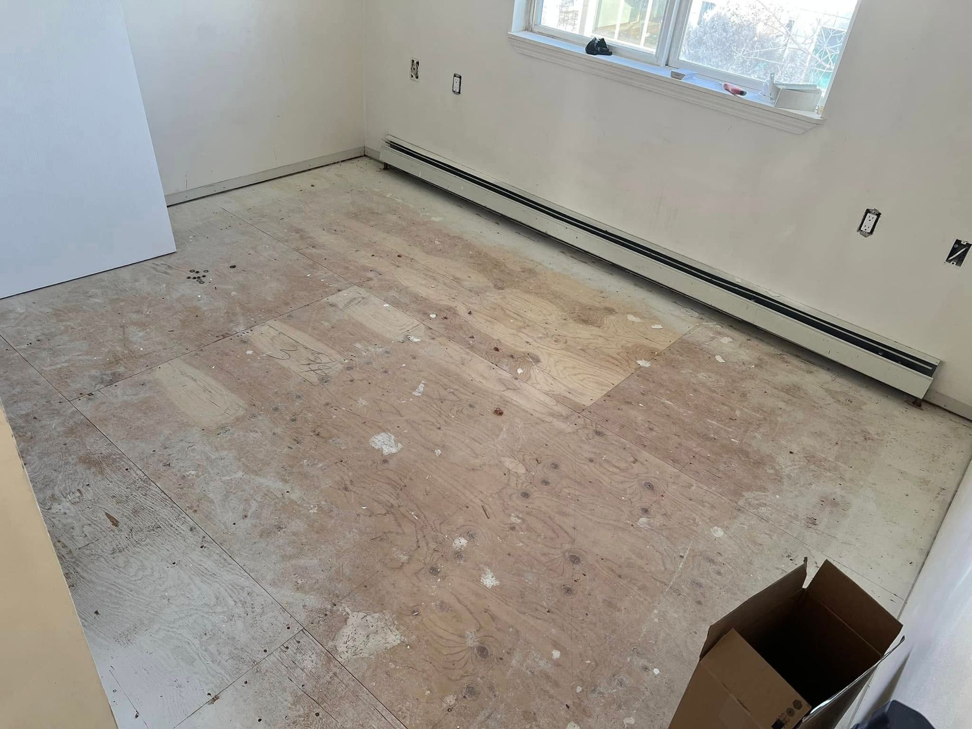 A room with a dirty floor and a box on the floor.