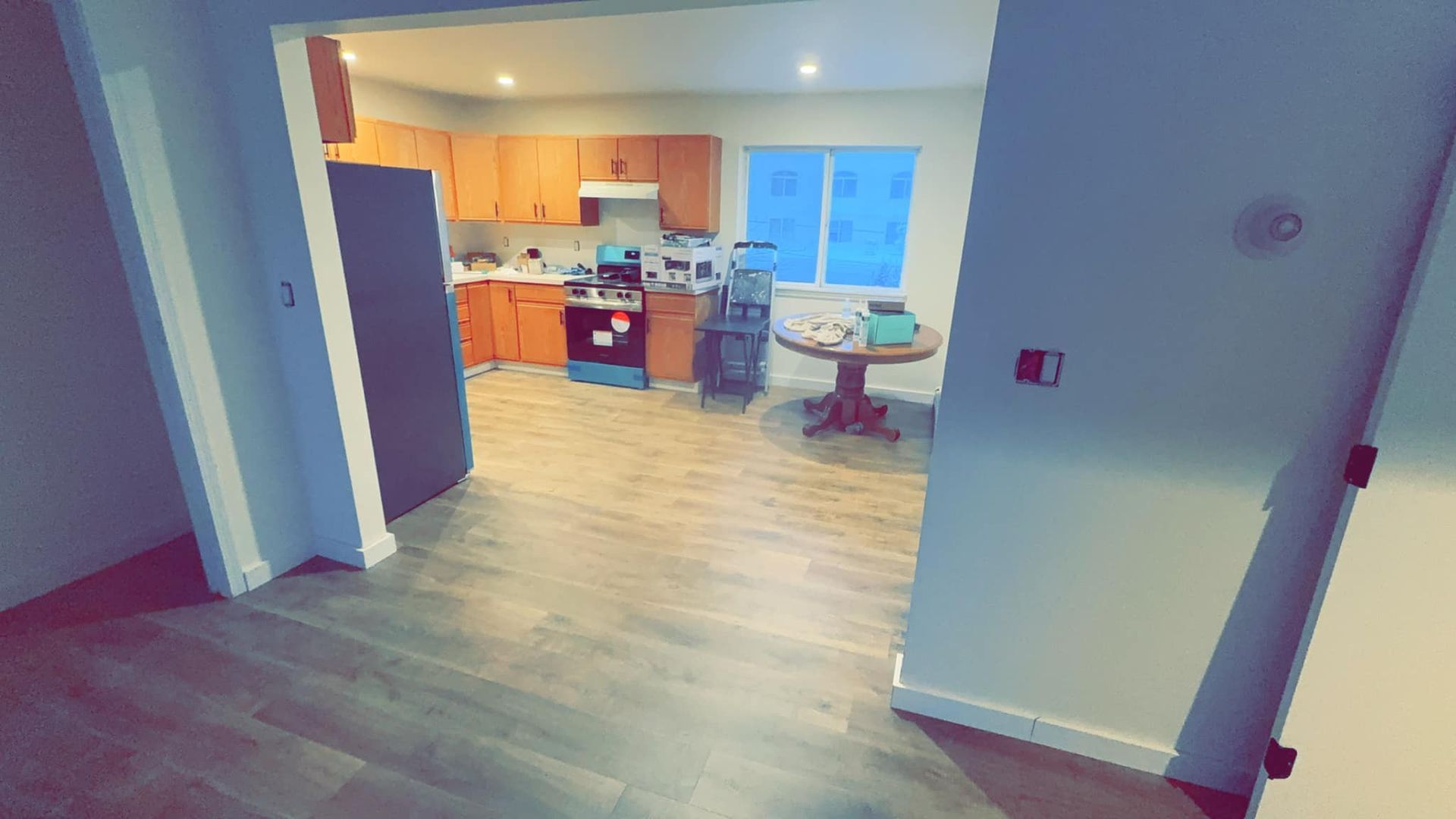 A kitchen with wooden cabinets , a stove , a refrigerator and a table.