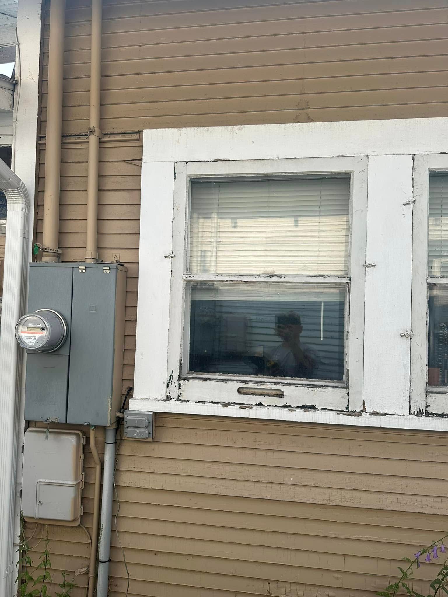 A man is looking out of a window on the side of a house.