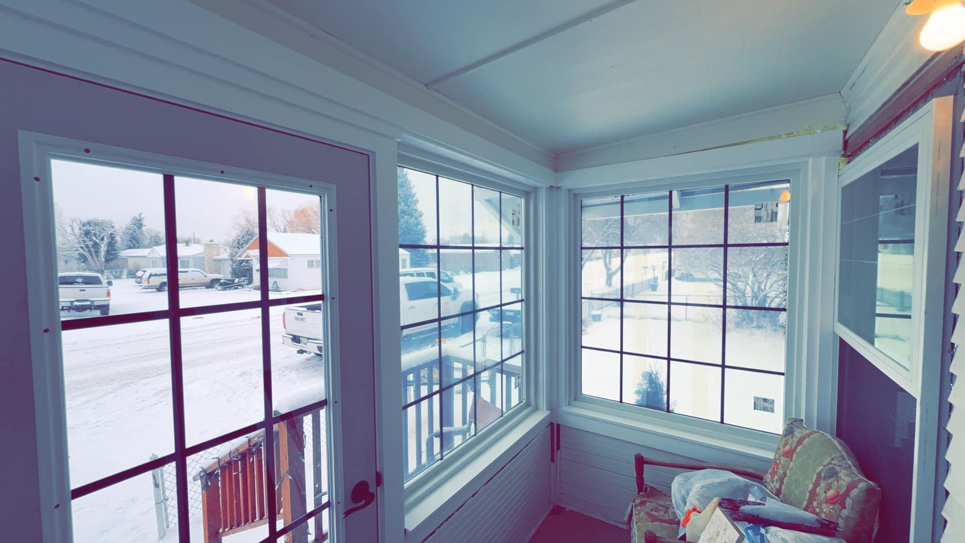 A room with a lot of windows and a chair in it.