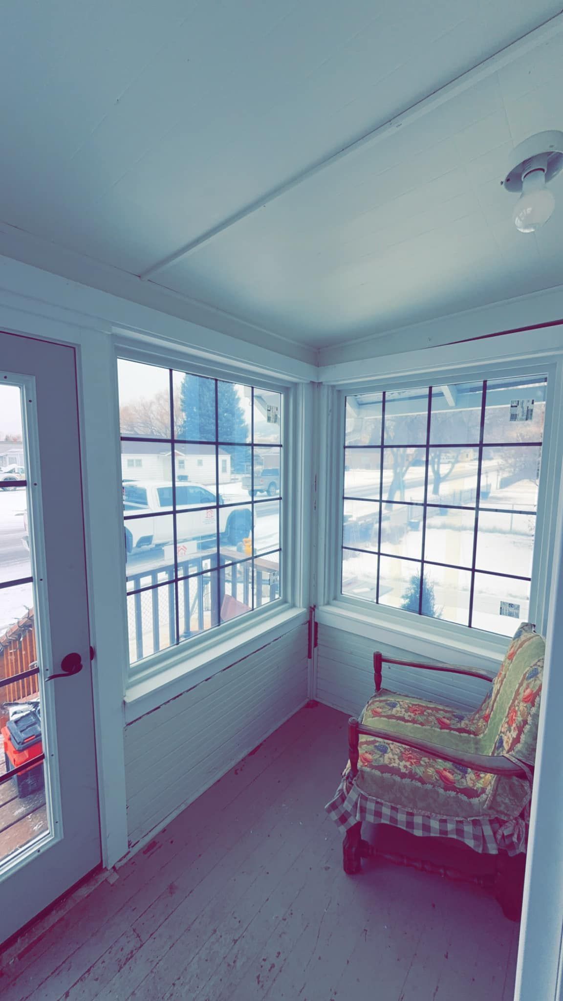 A chair is sitting in a room with a lot of windows.