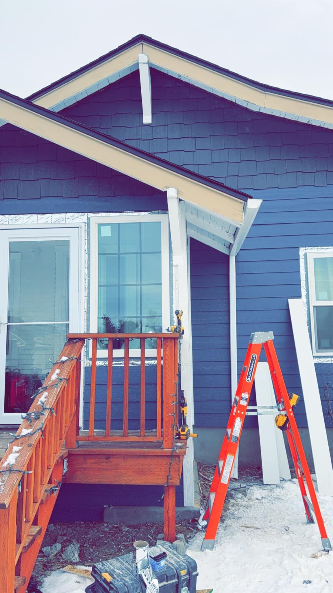 A blue house with a red ladder in front of it.
