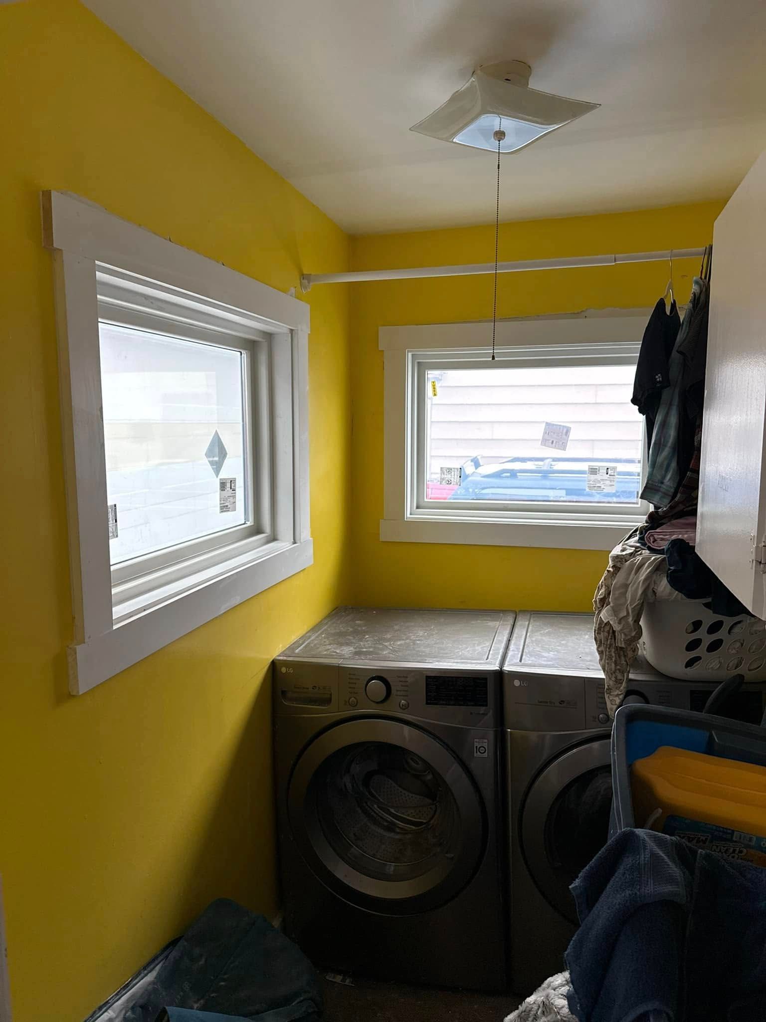 A laundry room with yellow walls , a washer and dryer , and a window.