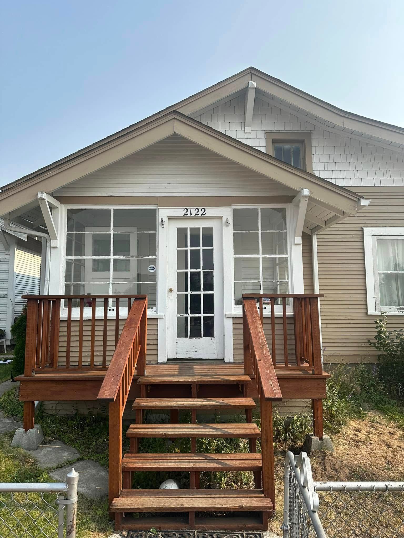 A small house with a porch and stairs leading up to it.