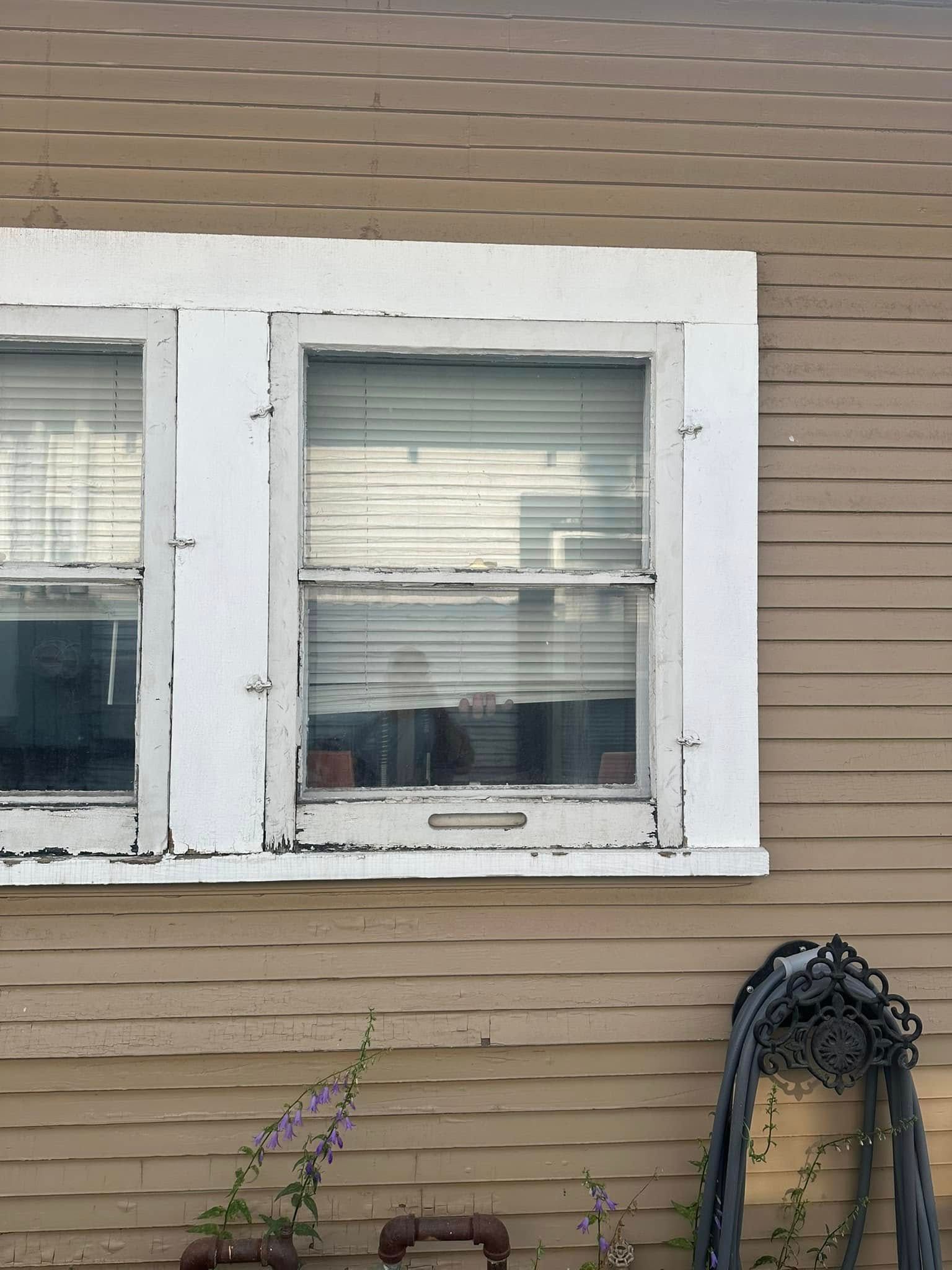 A window on the side of a house with blinds on it
