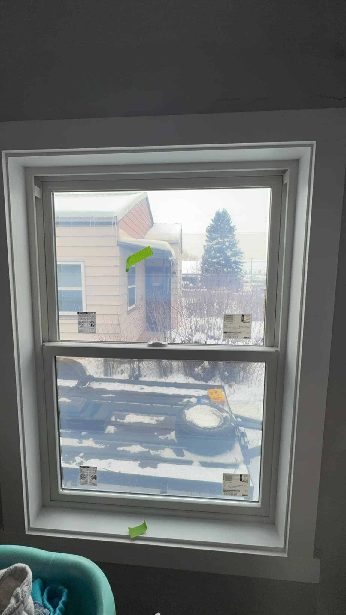 A window with a view of a snowy street and a house in the background.