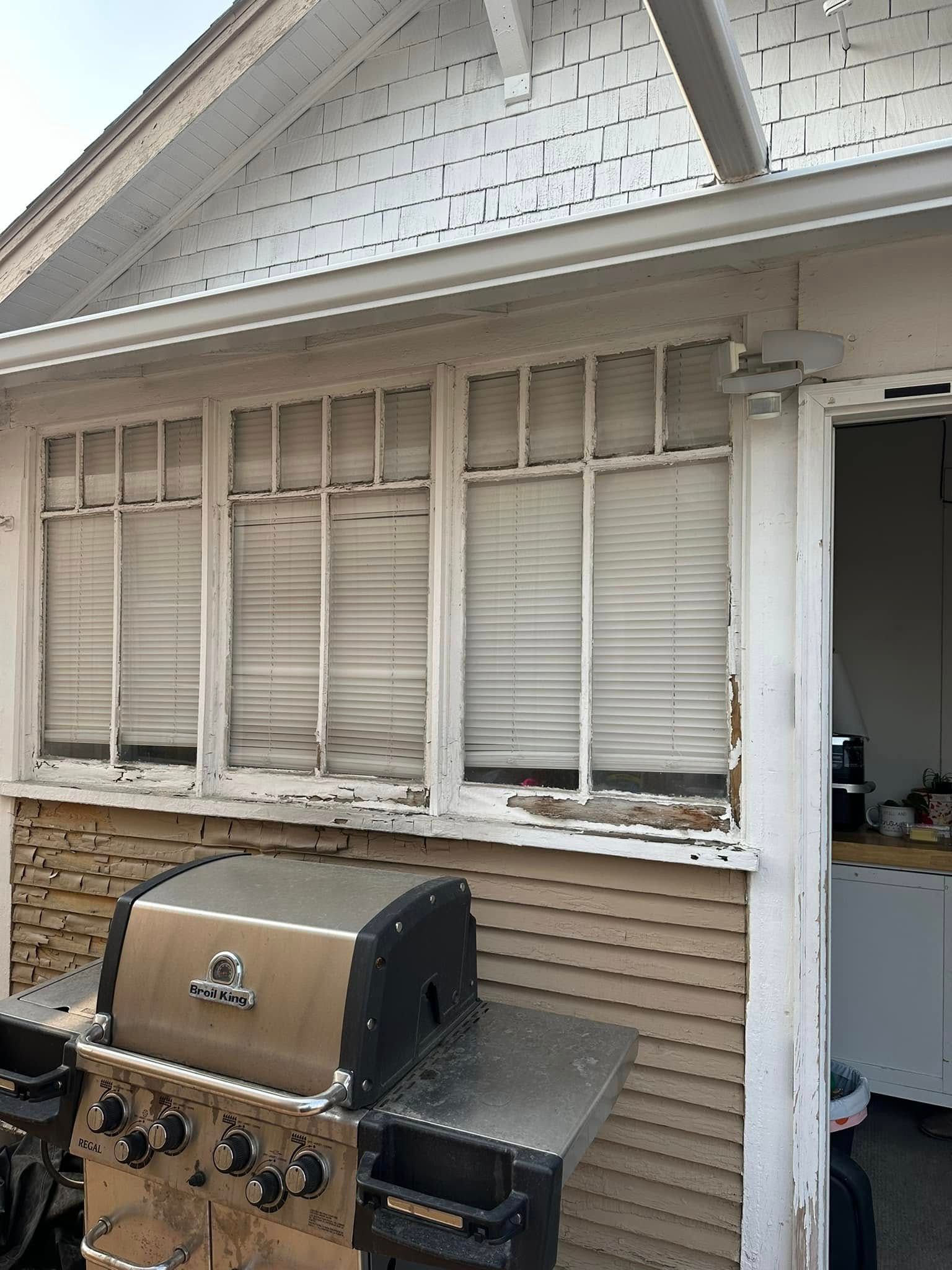 A grill is sitting in front of a house with a lot of windows.