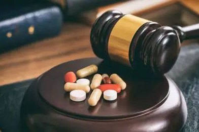 Judge’s gavel beside assorted pills on a dark surface