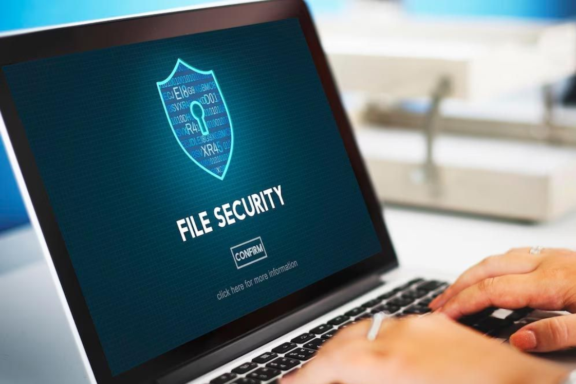 Laptop screen showing “file security” with a shield icon, while hands type on the keyboard
