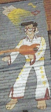 A painting of elvis presley playing a guitar on a brick wall