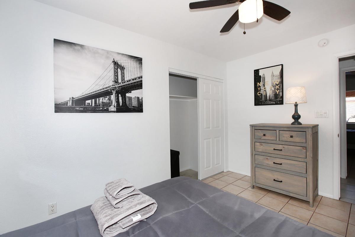 A bedroom with a ceiling fan and a picture of a bridge on the wall