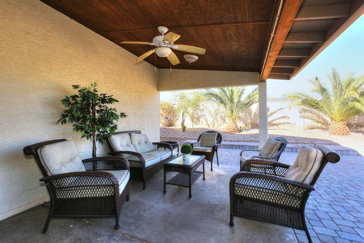 A patio with wicker furniture and a ceiling fan
