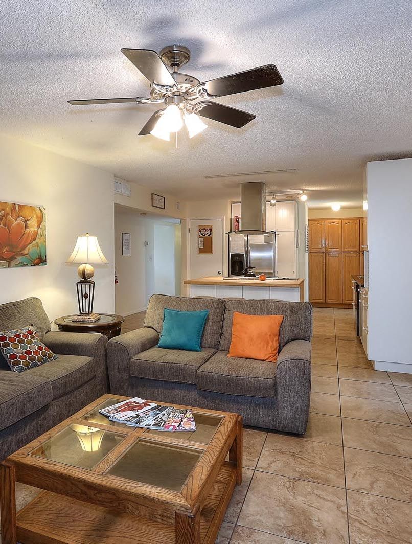 A living room with two couches , a coffee table , and a ceiling fan.