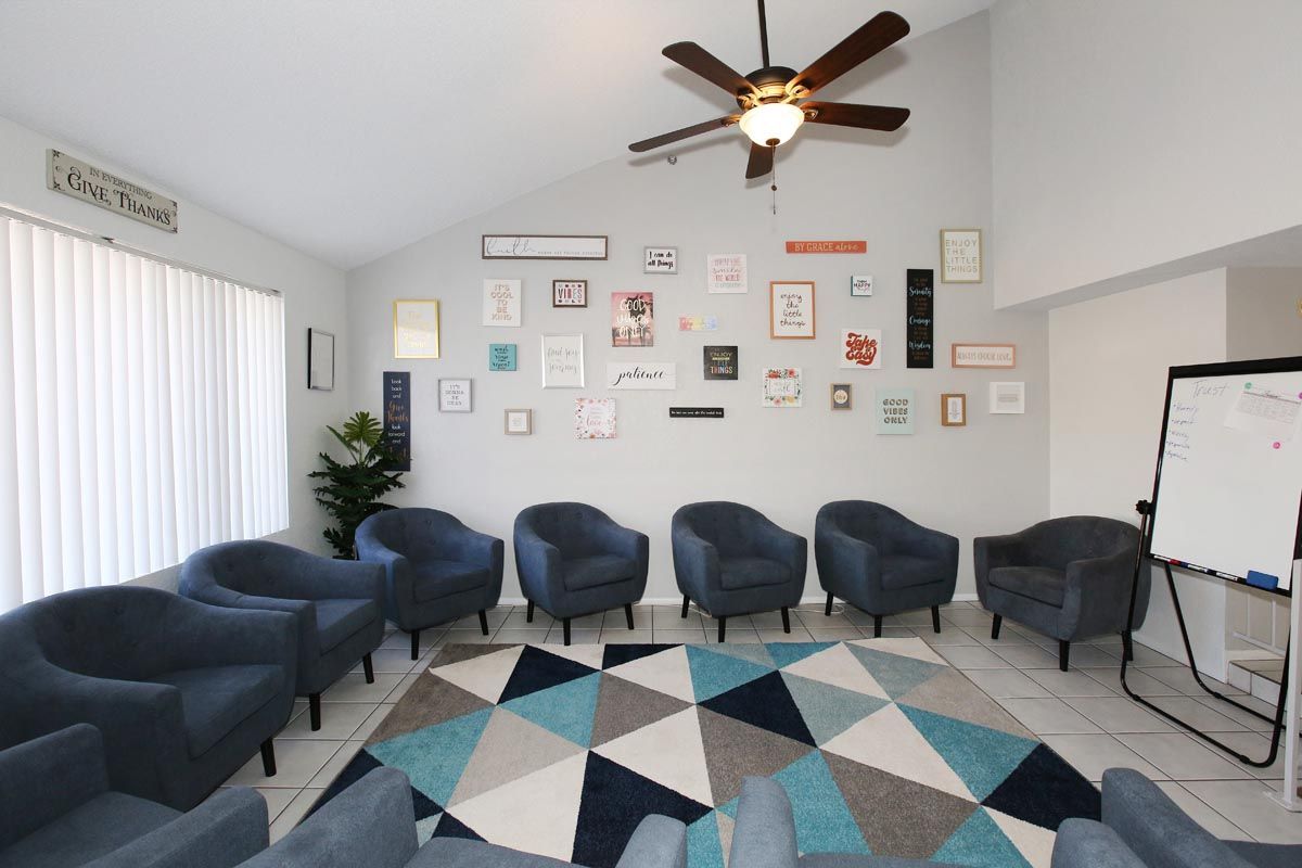 A room with chairs and a rug and a ceiling fan.